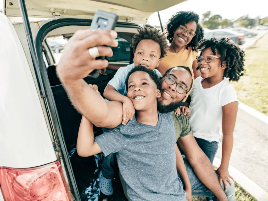 Familt aking a selfie outside a car. Road trip concept. Word games to play in the car