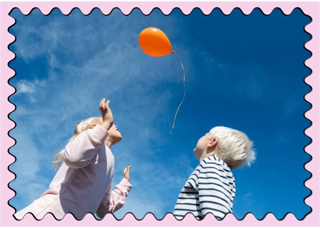 Kids releasing balloon in blue sky